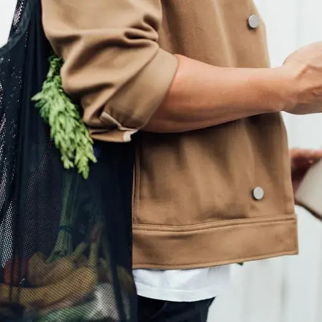 Donna che tiene in mano uno smartphone e una tazza di caffè da asporto