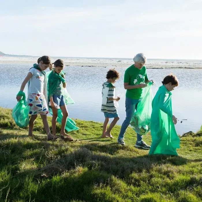 Bambini con la nonna che raccolgono i rifiuti da una spiaggia
