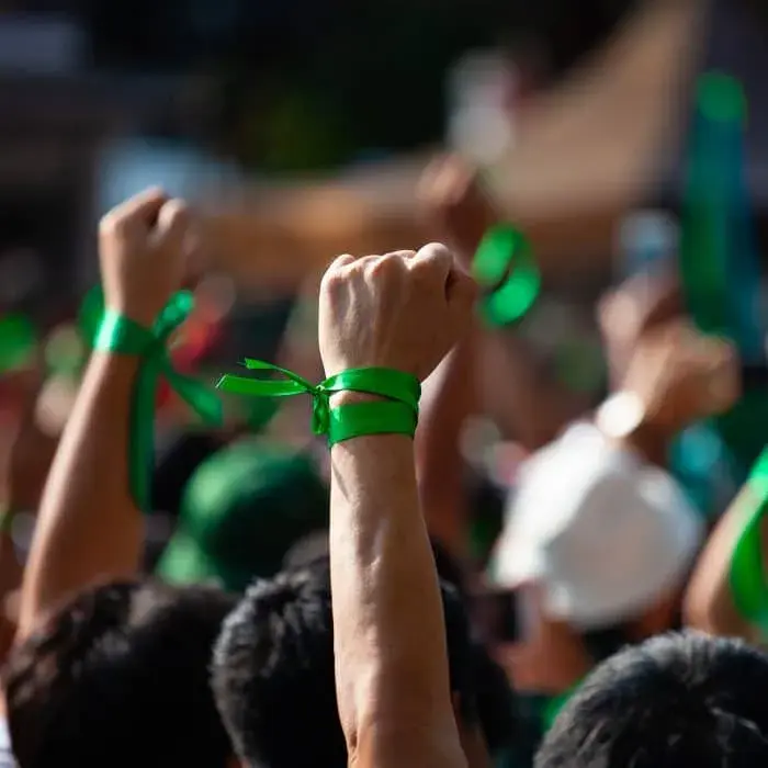 manifestanti con braccio alzato con un fiocco verde sul polso