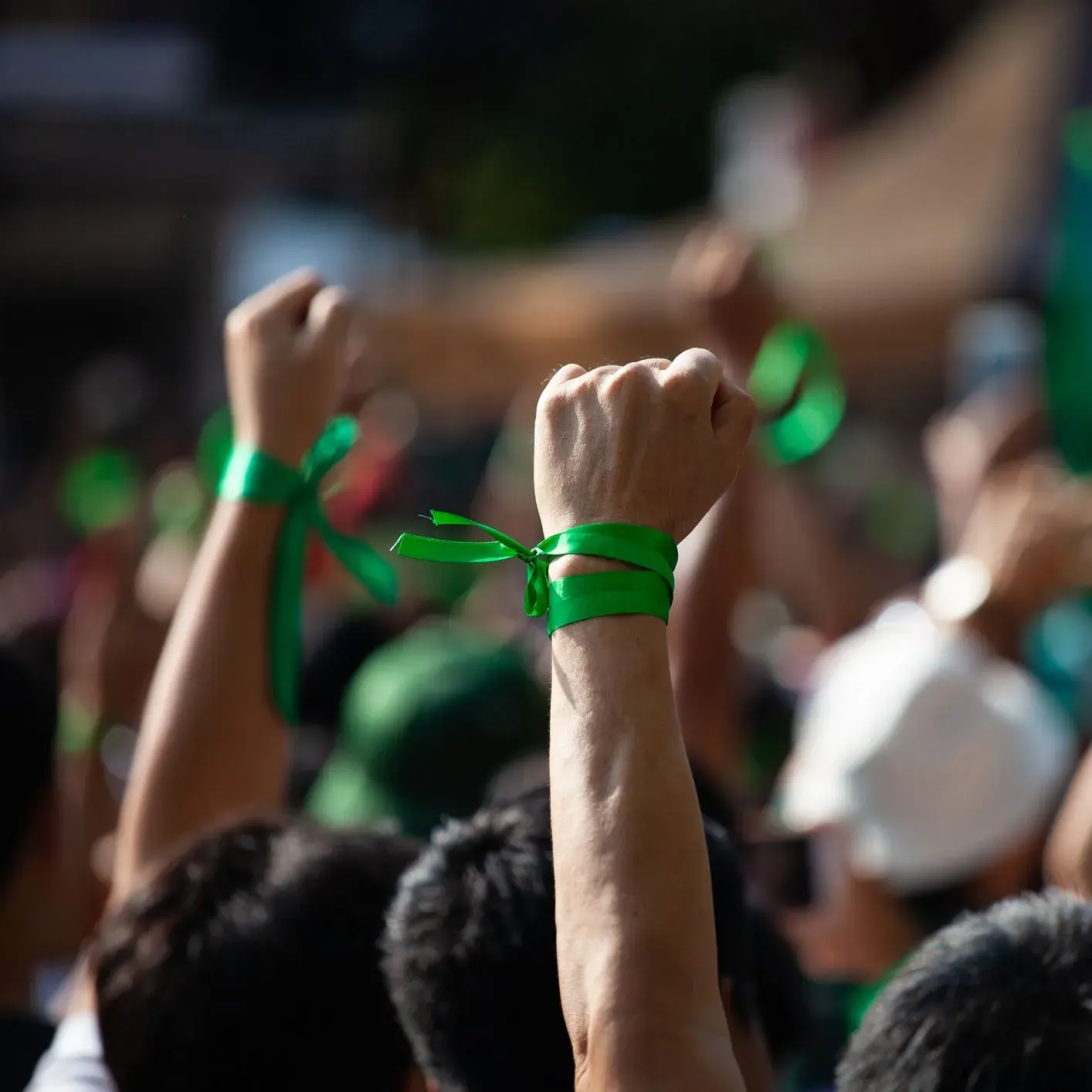 manifestanti con braccio alzato con un fiocco verde sul polso